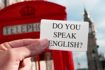 Student hält einen Zettel mit der Aufschrift "Do you speak English?" hoch und fragt damit, ob seine Fragen zum Personalmanagement Studium auch auf Englisch beantwortet werden können