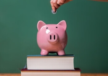 Student wirft eine Münze in ein Sparschwein, indem er für seine Studienfinanzierung spart